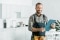 smiling handsome plumber holding clipboard and looking at camera in kitchen; Shutterstock ID 1192486621; Purchase Order: 040